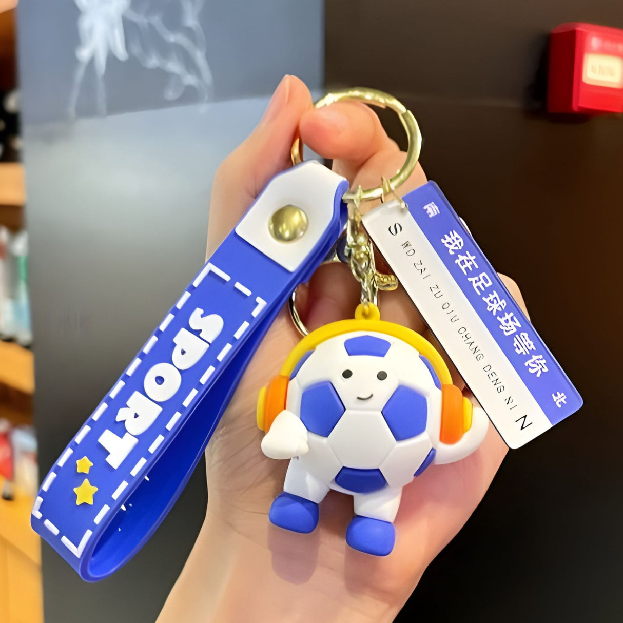 Detaliu breloc Flippy minge fotbal cu căști și mesaj decorativ imprimat, acril albastru închis